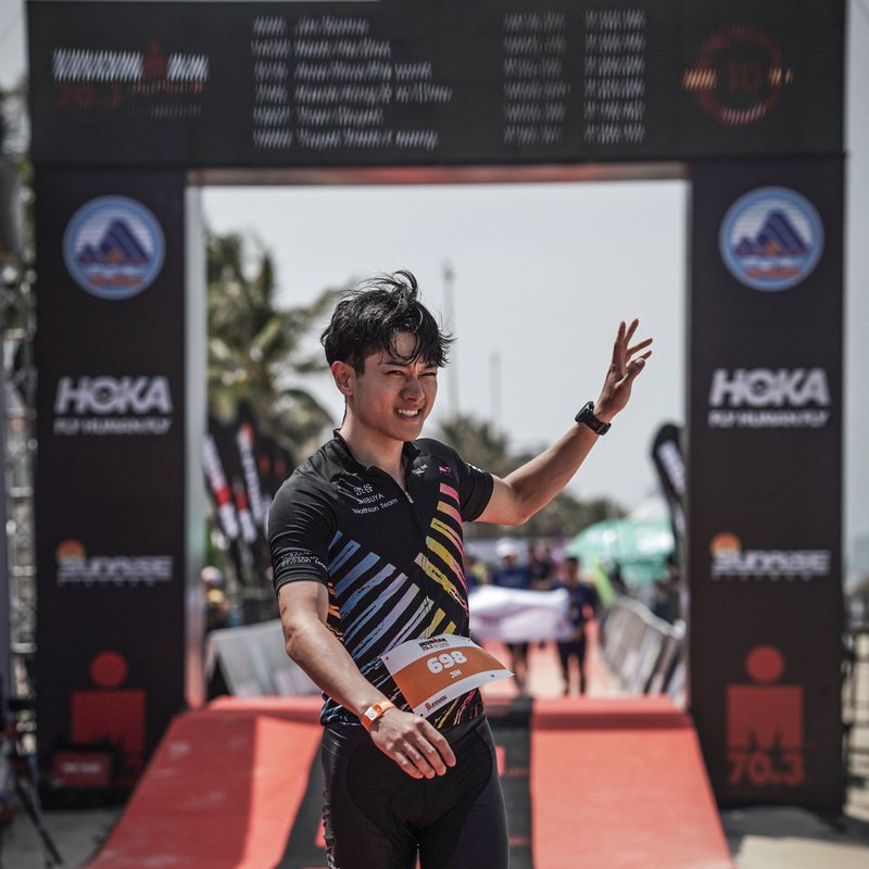Jin waving at the IRONMAN 70.3 finish arch in Da Nang